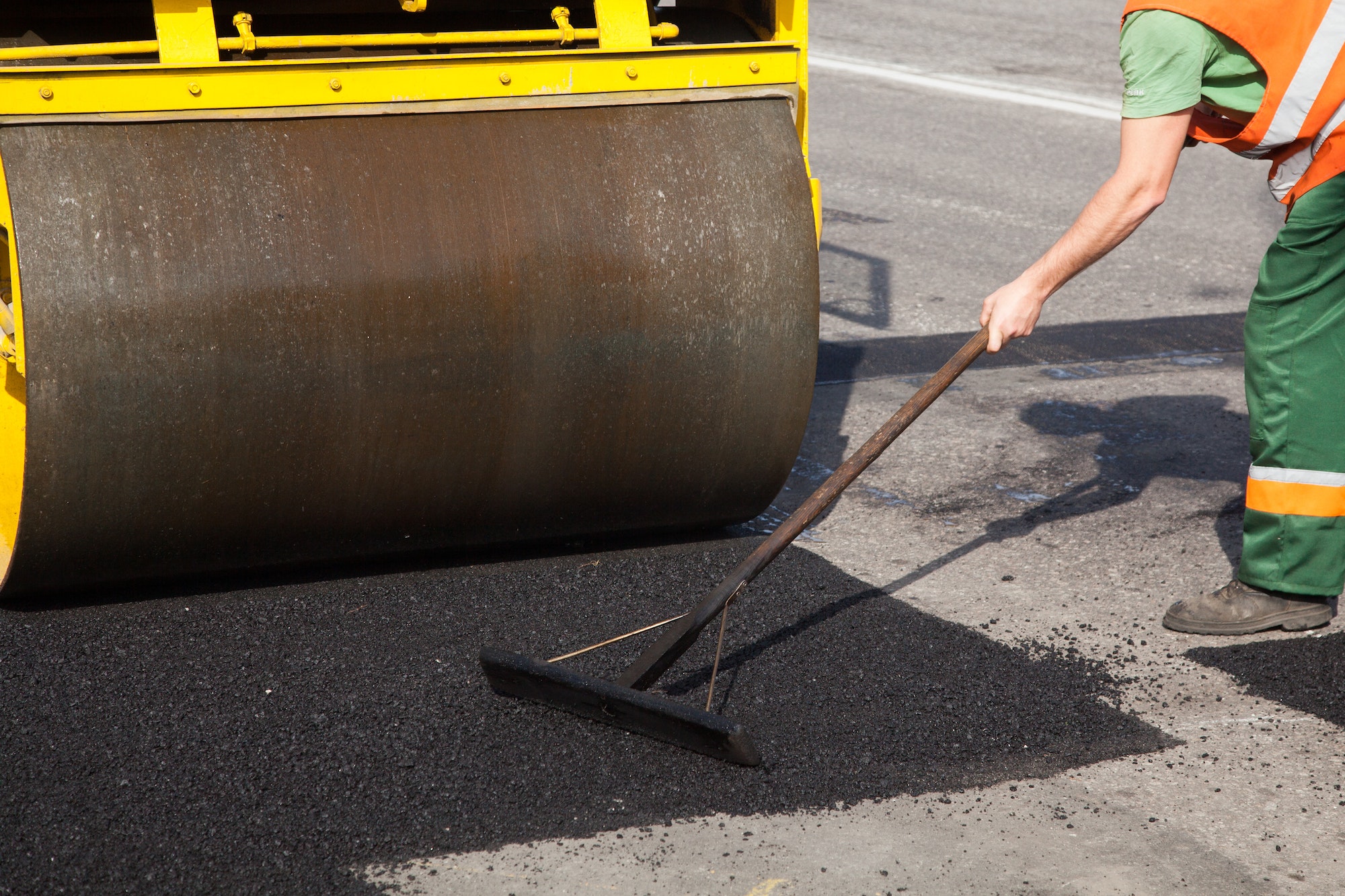 Pavement machine laying fresh asphalt or bitumen on top of the gravel base during highway
