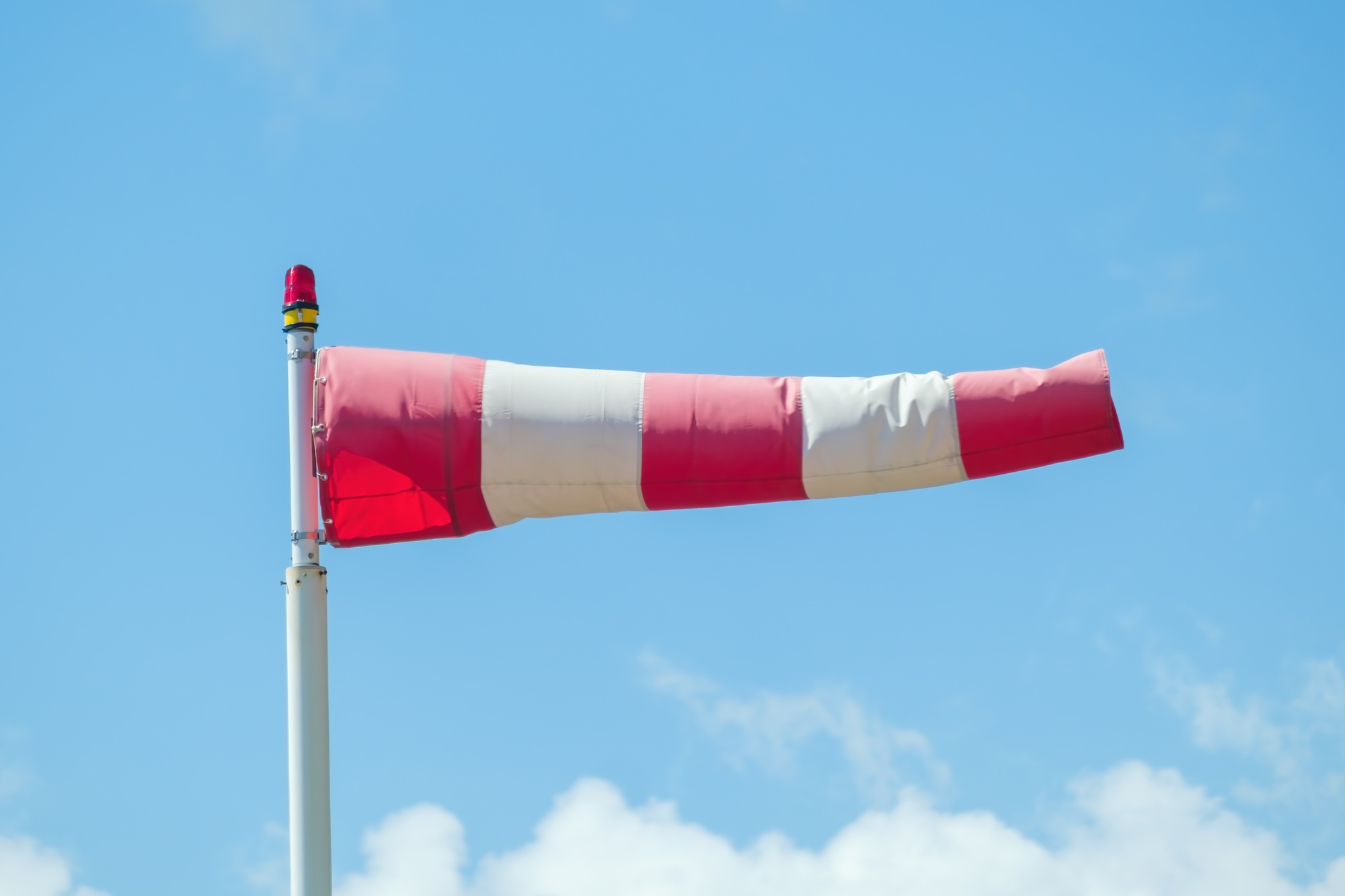 Windsock against a blue sky and clouds showed the wind direction